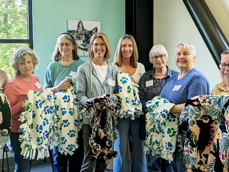 group of volunteers holding handmade blankets